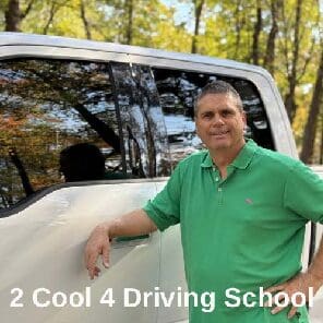 Here's an alt tag for the image: `Driving instructor leaning on truck`